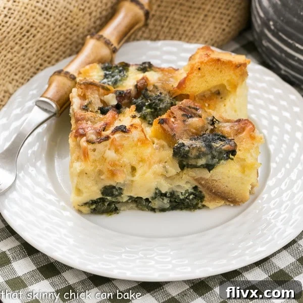 Gruyere Spinach Strata slice on a white plate with a bamboo handle fork.