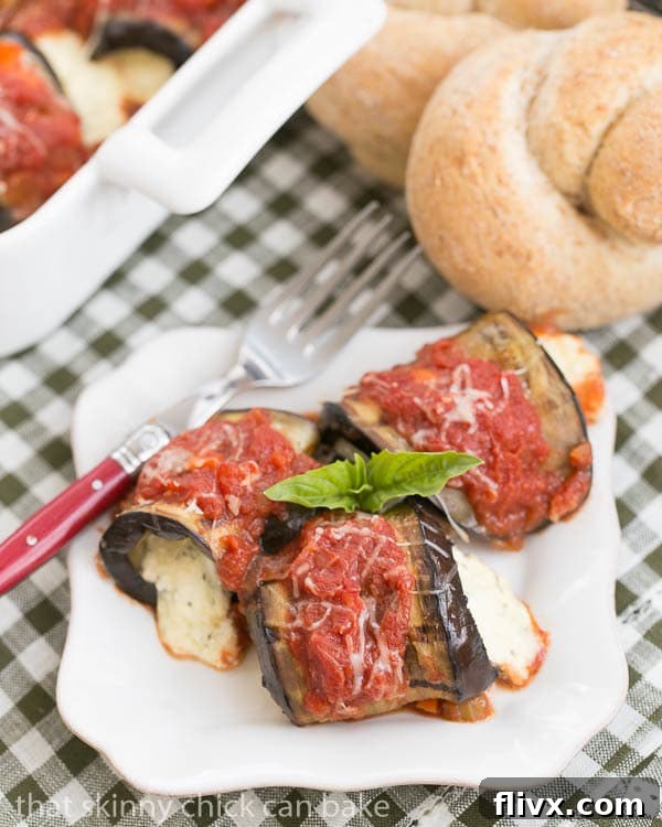 Eggplant Rollatini with Ricotta and Mozzarella on a square white plate garnished with fresh basil