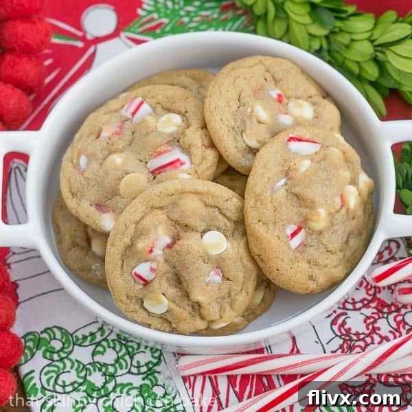 Candy Cane Crunch White Chocolate Delights 3 A plate of White Chocolate Candy Cane Cookies, showcasing their golden edges, soft centers, and festive white chocolate and peppermint pieces, against a blurred holiday backdrop.