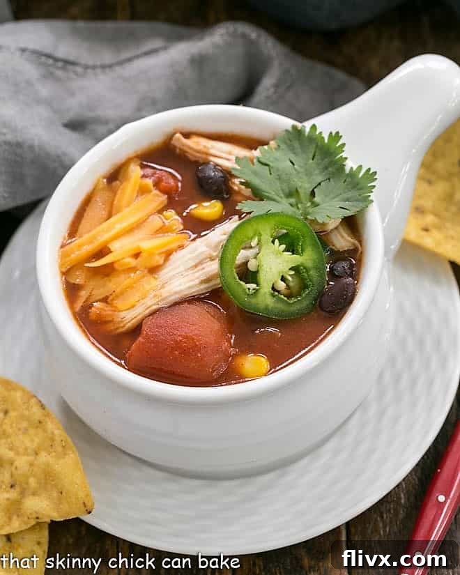 Slow Cooker Chicken Enchilada Soup in a soup bowl on a white plate.