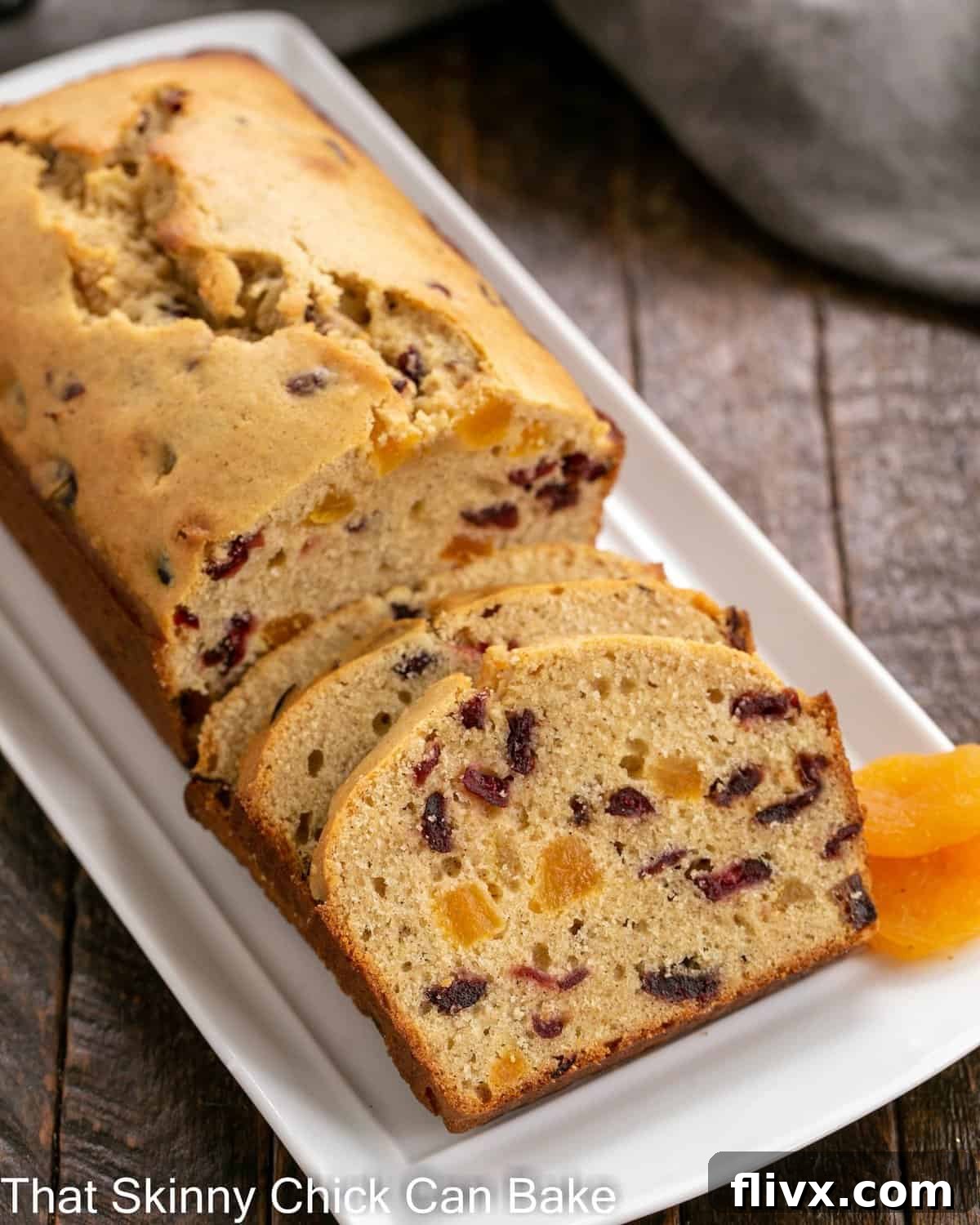 Apricot Quick Bread partially sliced with dried apricots to garnish on a white tray.