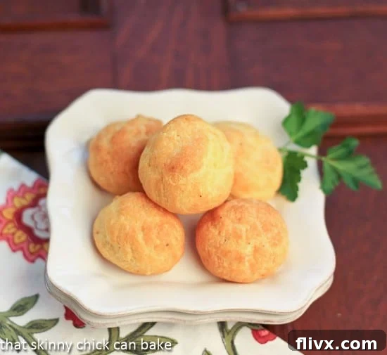 Overhead close-up view of perfectly baked Parisian Cheese Puffs on a clean white plate, ready for serving