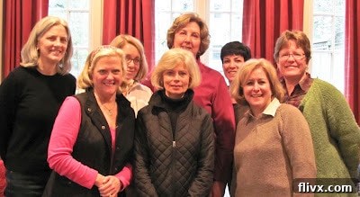 A group of friends laughing and gathered together for a baking lesson, showing camaraderie and shared enjoyment