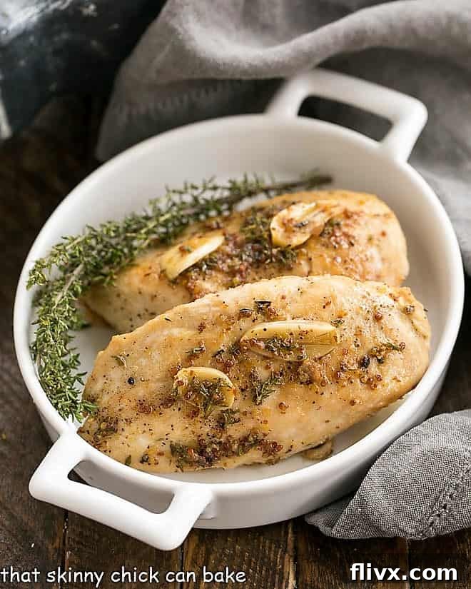 Maple Mustard Glazed Chicken Breasts in a white dish with handles, garnished with fresh thyme