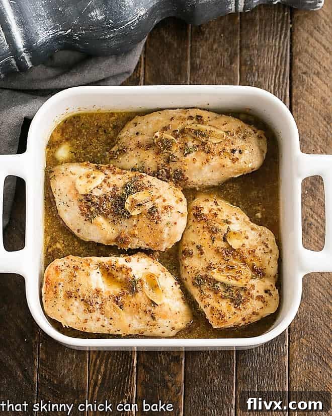 Maple Mustard Chicken Breasts baking in a glass dish, coated in golden glaze