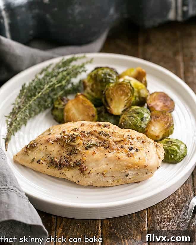 Mustard Maple Chicken Breast on a white dinner plate with roasted Brussels sprouts