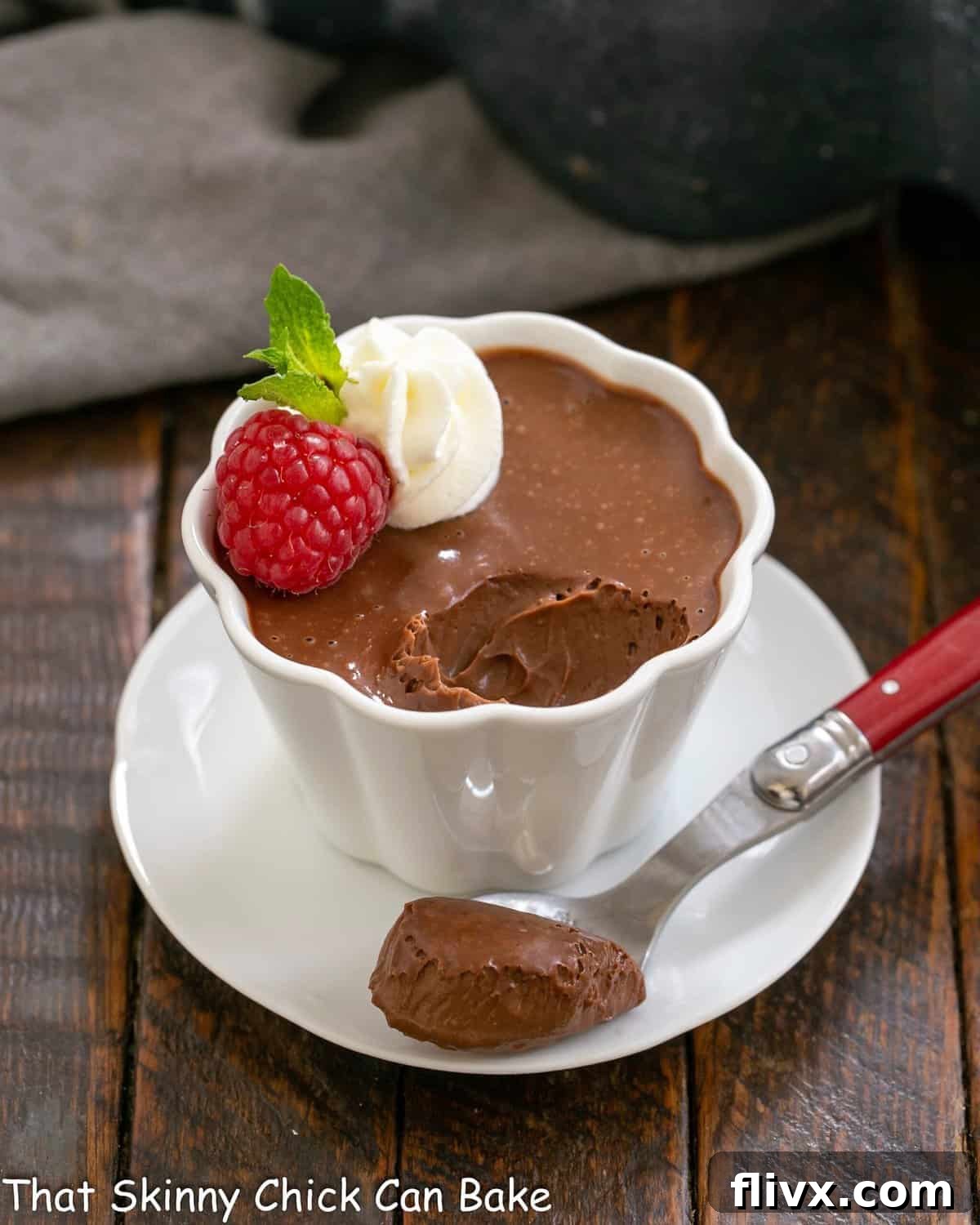 A perfectly set Irish cream pots de creme in a pristine white ramekin, with a spoonful delicately removed, showcasing its smooth, creamy texture and rich chocolate hue. Garnished with fresh raspberries and a dollop of whipped cream, inviting immediate indulgence.
