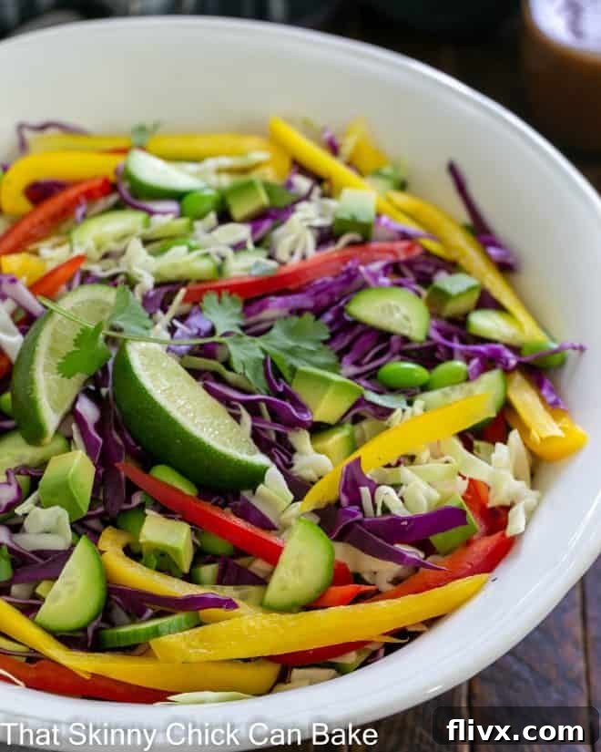 Large white ceramic serving bowl filled with colorful Thai Crunch Salad, garnished with fresh cilantro and crushed peanuts.