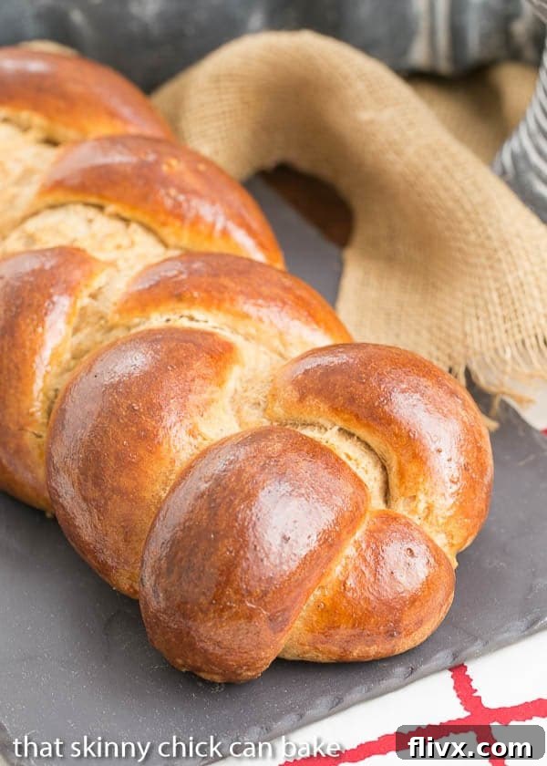 A beautifully braided Whole Wheat Challah loaf resting on a slate tray.