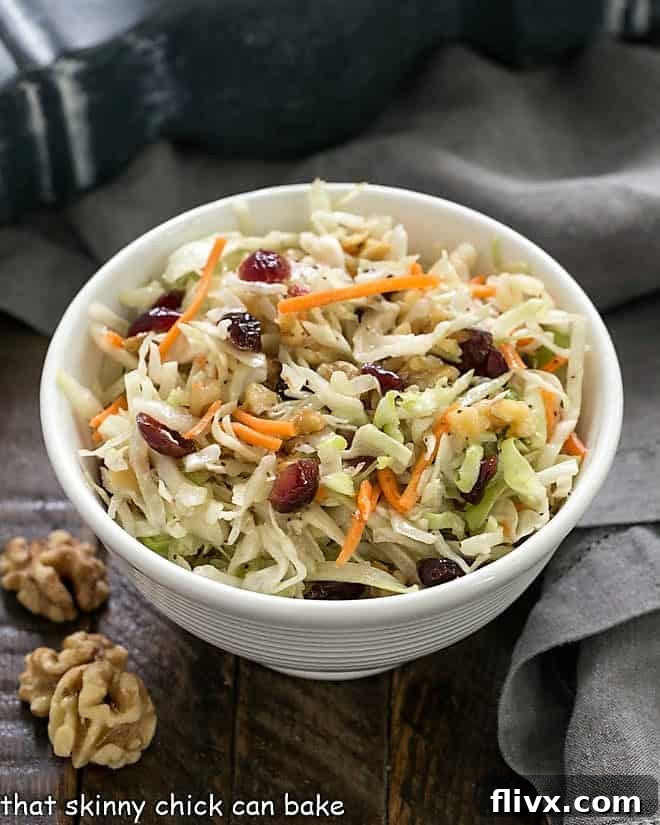 Easy coleslaw in a white bowl with walnuts to garnish, ready to be served.