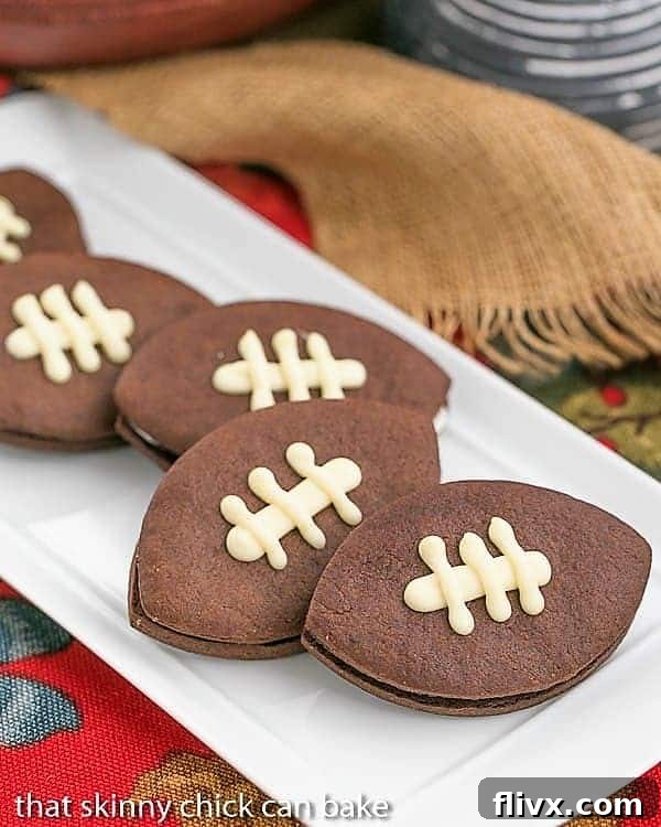 A white platter showcasing a delicious array of Chocolate Football Cookies, each adorned with white chocolate laces and filled with buttercream and caramel.
