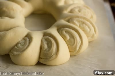 Tea ring dough filled, rolled, and risen on a parchment-lined baking sheet, ready for the oven