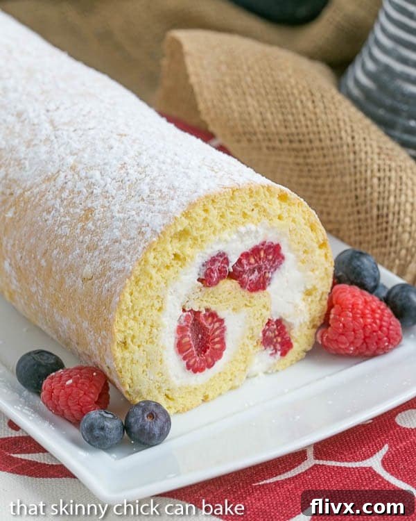 Berry Roulade on a white serving tray with a garnish of fresh berries.