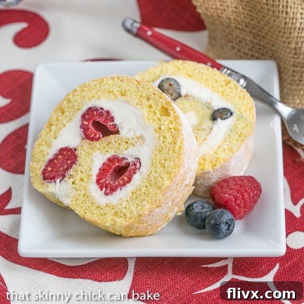 Slices of Berry Roulade on a square white plate with fresh berries to garnish.