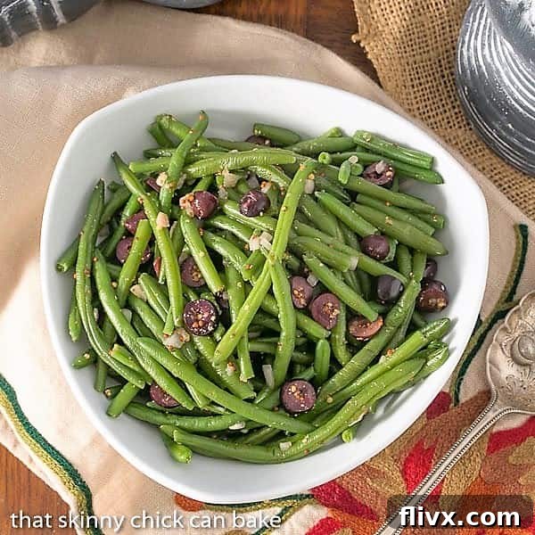 Overhead view of a bowl of mustardy haricots verts with Kalamata olives and fresh parsley