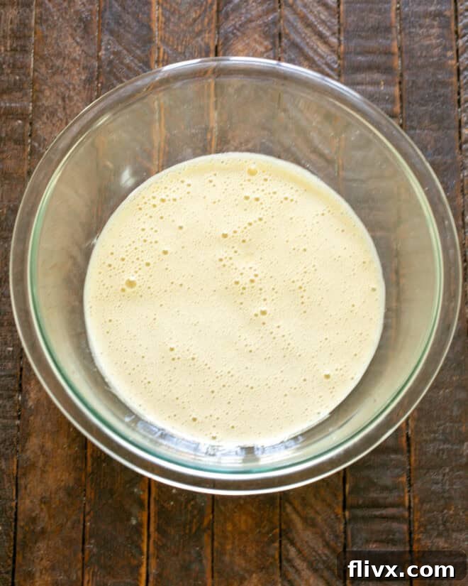 Eggs, sugar, espresso, and vanilla extract being vigorously beaten together in a stand mixer.