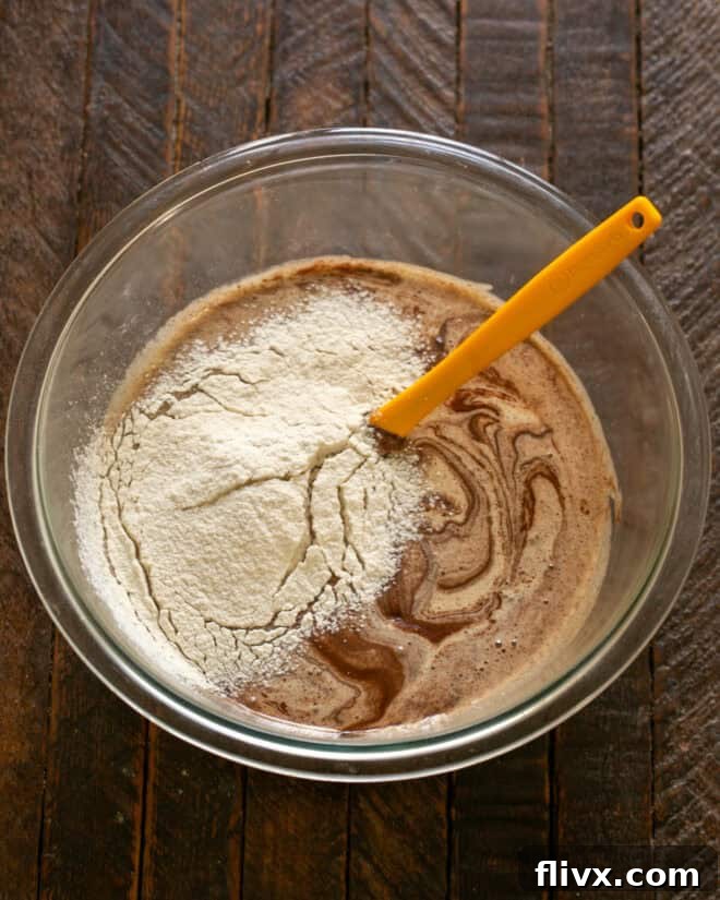 A sifter gently sifting flour, salt, and baking powder into the cookie batter.
