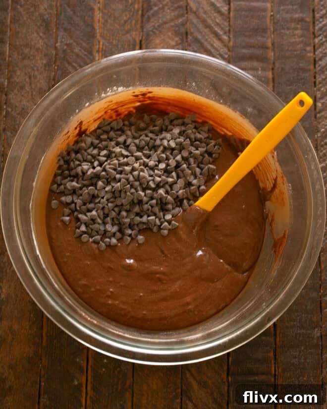 Mini chocolate chips being folded into the brownie cookie dough, ensuring even distribution.