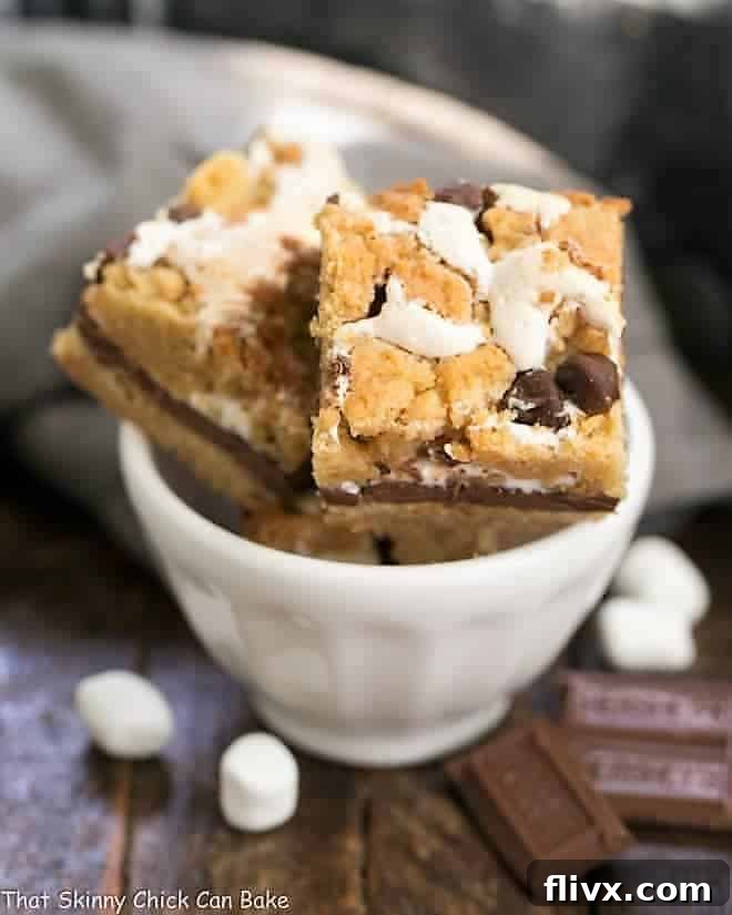 A small stack of S'mores Cookie Bars in a white bowl, showing their delightful layers.