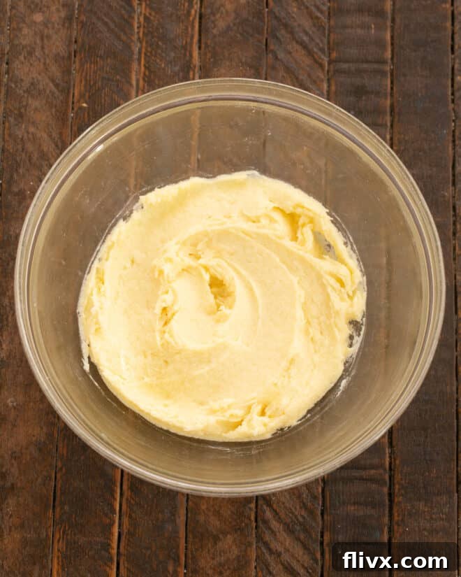 Adding an egg and vanilla extract to the creamed butter and sugar mixture.