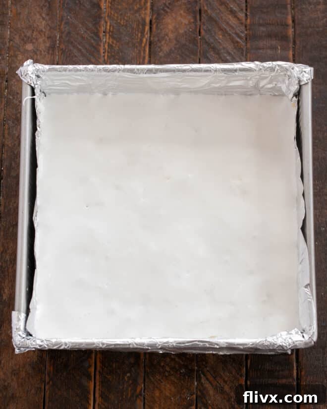 Spreading marshmallow cream evenly over the chocolate bars with a damp knife.