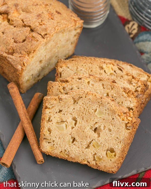 Close-up of Cinnamon Spiced Apple Bread slices and a partial loaf on a rustic slate tray, showcasing its tender crumb.