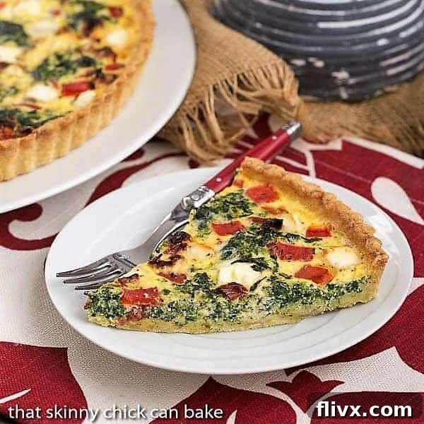A perfectly sliced Sun-dried Tomato and Spinach Quiche on a white plate, ready to be enjoyed with a red-handled fork.