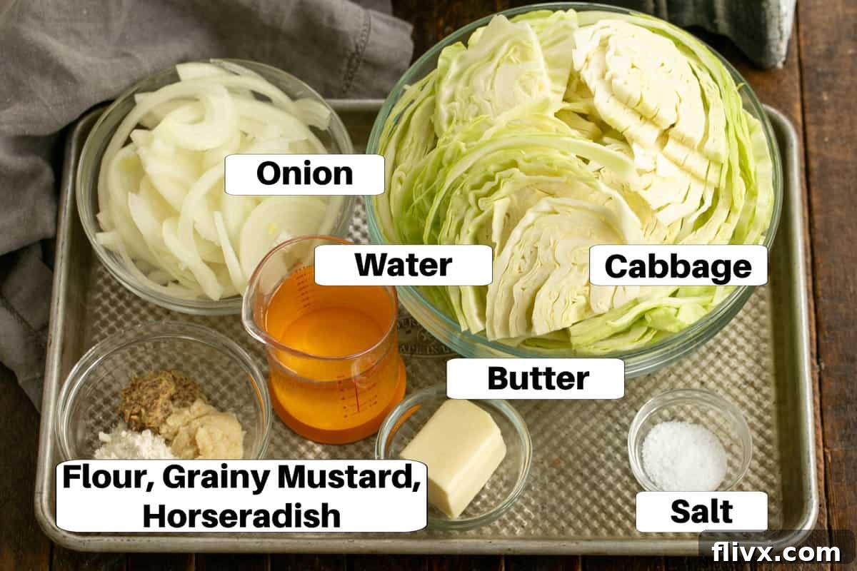 Fresh ingredients for Sauteed Cabbage with Mustard, including whole cabbage, onion, butter, mustard, and horseradish, laid out on a sheet pan.