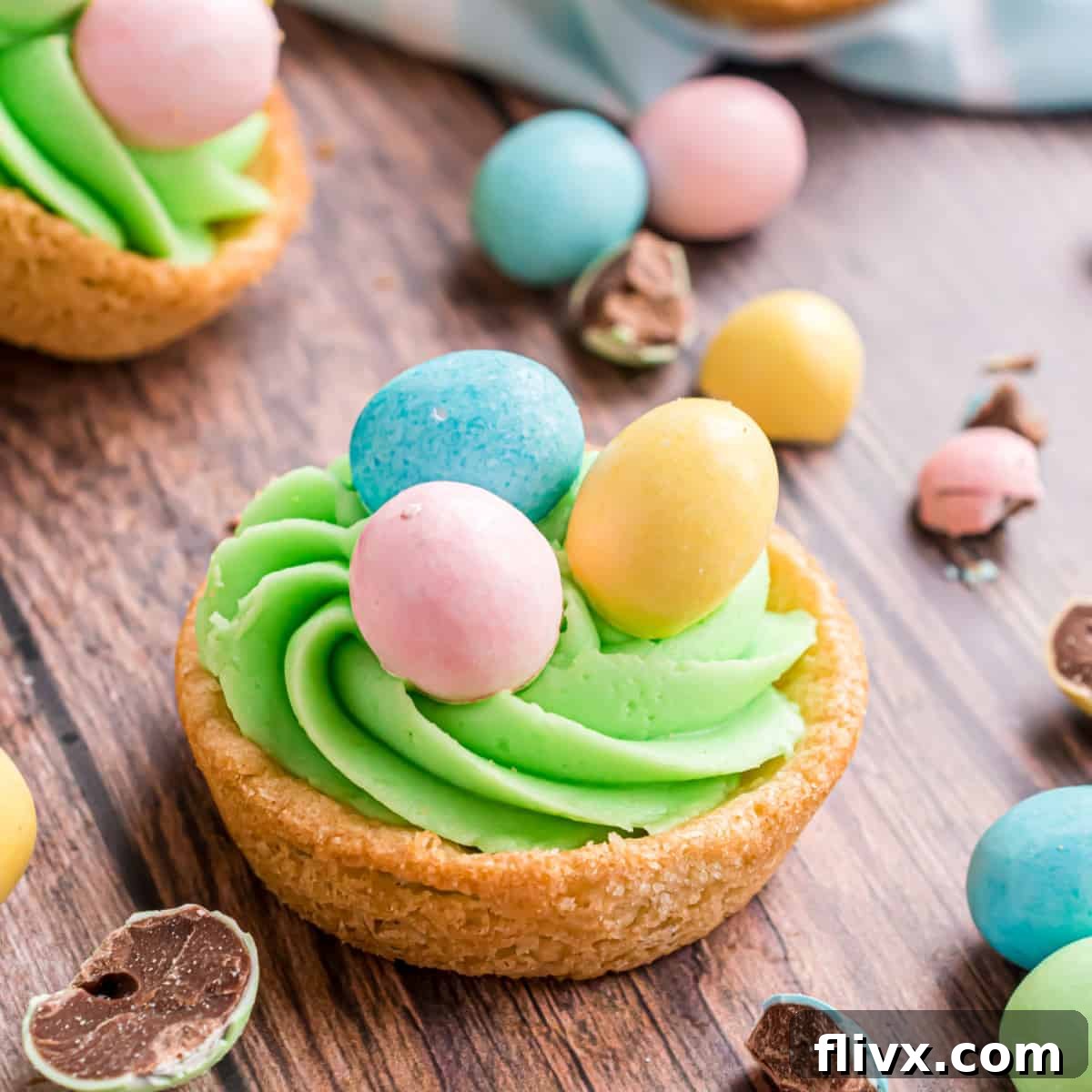 Festive Easter Sugar Cookie Cups filled with frosting and topped with colorful egg candies.