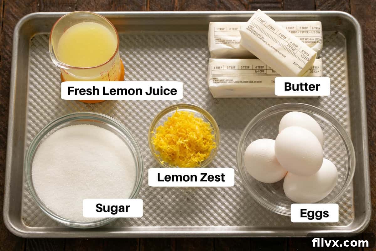 Lemon Tart Filling Ingredients laid out on a sheet pan with labels, featuring fresh lemons, eggs, sugar, and butter.