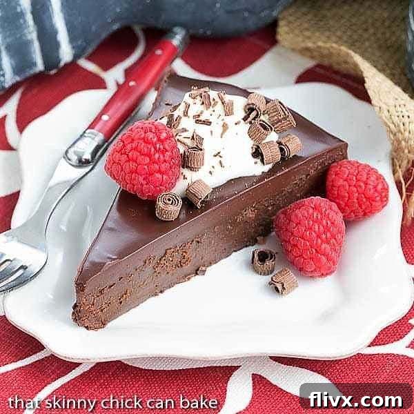 La Bete Noire - Dark, decadent and out-of-this-world delicious flourless chocolate cake recipe A rich, decadent slice of La Bete Noire, a French flourless chocolate cake, served on a white plate with a red handle fork, highlighting its dense, dark texture.