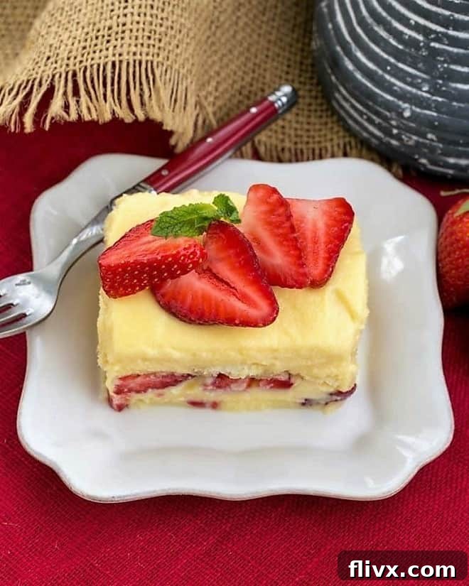 Berry Tiramisu with Grand Marnier - A strawberry twist on the Italian classic with mascarpone and Grand Marnier soaked ladyfingers! A close-up of Berry Tiramisu with Grand Marnier, garnished with fresh strawberry slices and a hint of mint, served on a square white plate.