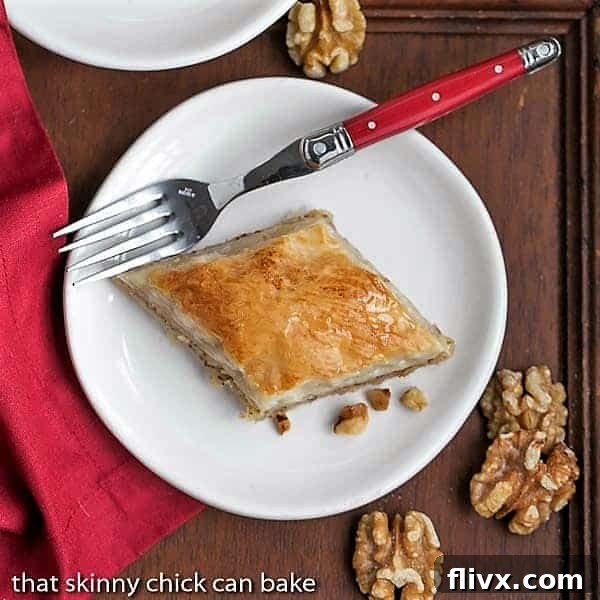 Overhead view of a slice of Classic Greek Baklava on a white plate, showcasing its golden layers and nutty filling.