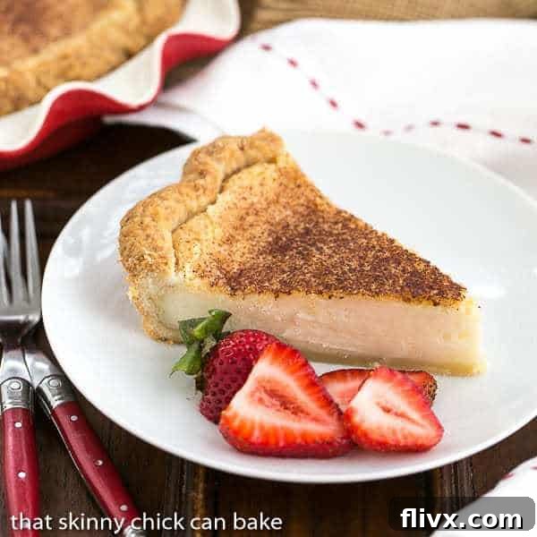 A perfectly baked slice of Hoosier Sugar Cream Pie, served on a white plate with fresh strawberry slices, highlighting its creamy texture.