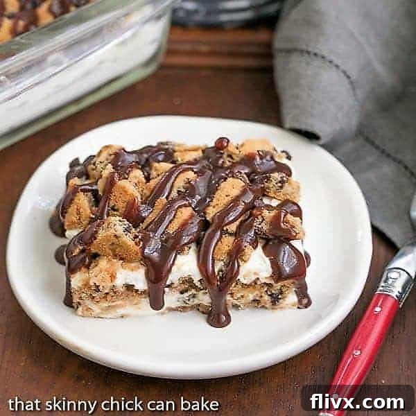 A perfectly sliced piece of Milk and Cookies lasagna on a white plate with a red handle fork, showcasing its luscious layers.