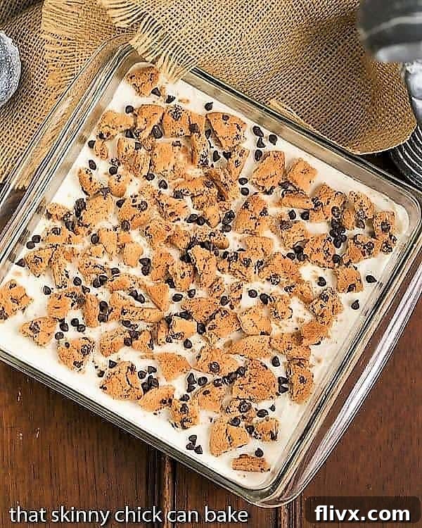 Overhead view of a beautiful Milk & Cookies Lasagna setting in a square, clear glass baking pan, ready to be chilled.