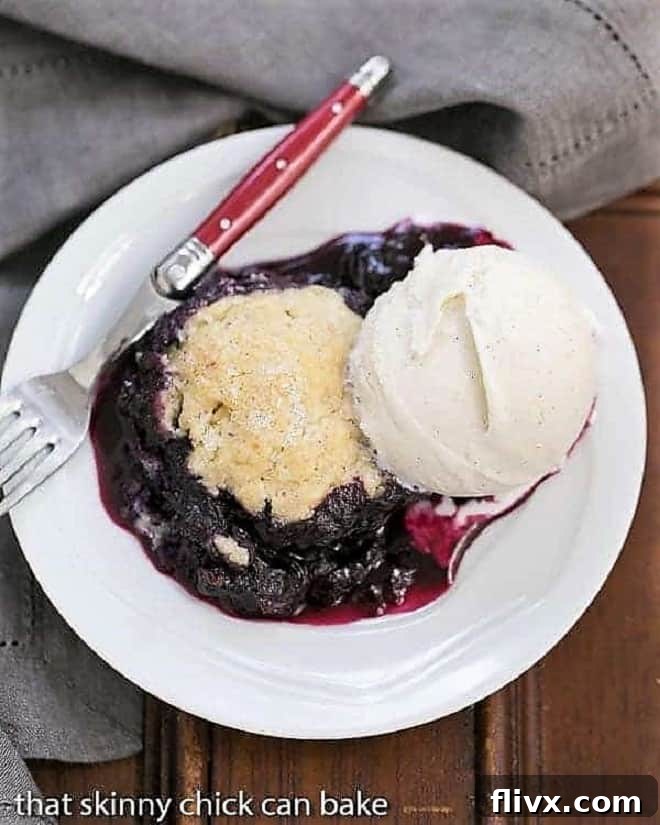 Grilled Blueberry Cobbler a la mode on a white plate with a red handled fork.