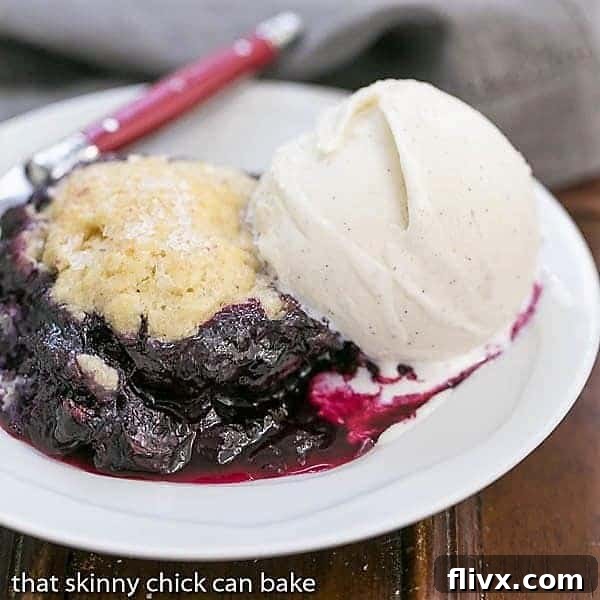 Grilled Blueberry Cobbler on a white dessert plate topped with a scoop of ice cream.