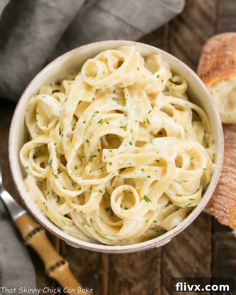 Overhead view of a bowl of Light Fettuccine Alfredo, highlighting its creamy texture and fresh parsley garnish.