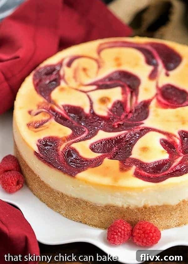 A stunning slice of White Chocolate Raspberry Swirl Cheesecake on a white plate, elegantly garnished with fresh raspberries, showcasing its vibrant layers and creamy texture.