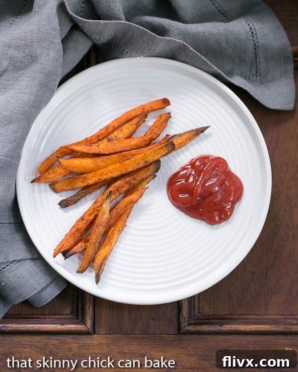 Overhead view of Spicy Sweet Potato Fries on a white plate with ketchup, ready to be served and enjoyed.