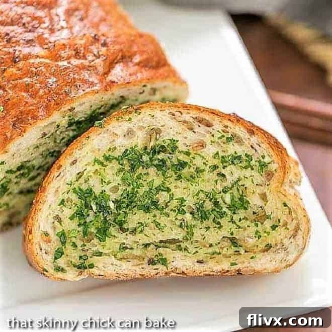 Herb Garlic Bread slice next to loaf on a white platter