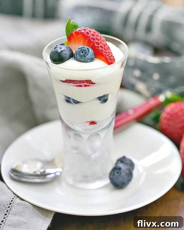 White Chocolate Berry Parfaits on a small white plate with a red handle spoon, showcasing layers of white chocolate mousse and mixed berries