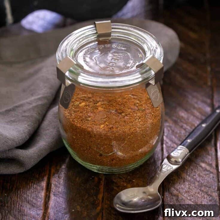 Square image of Taco seasoning in a glass container with a black handled spoon.