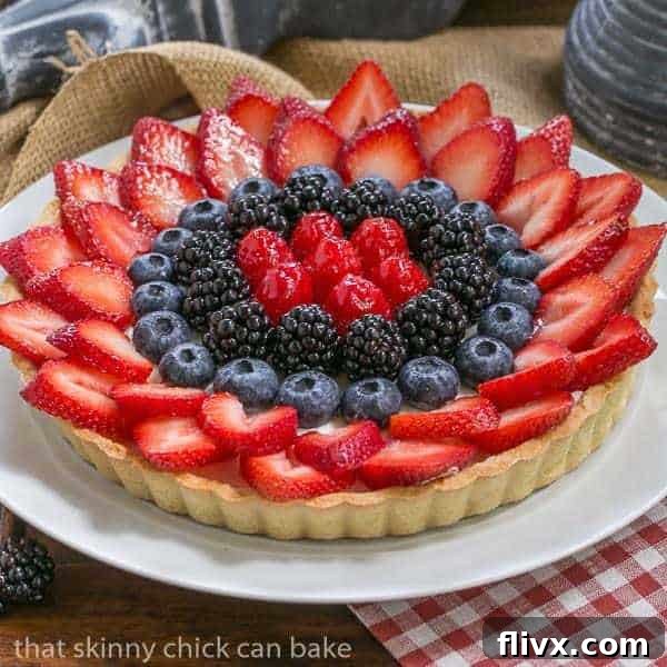 A stunning Summer Fruit Tart with a variety of fresh berries arranged on top of a cream cheese filling.
