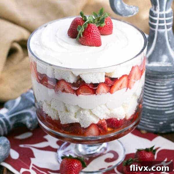 A towering Strawberry Cheesecake Trifle, revealing layers of angel food cake, berries, and cream cheese filling.