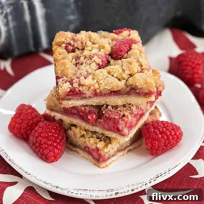 Stack of Streusel Topped Raspberry Cookie Bars on a small round white plate, ready to be enjoyed.