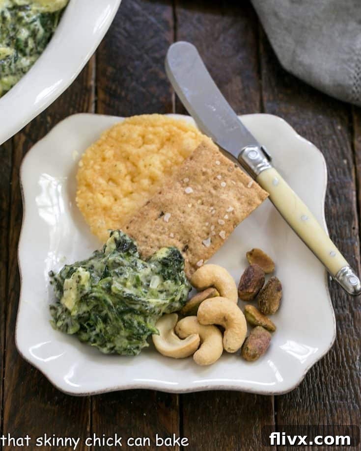 Gooey Cheesy Spinach Dip with artichoke hearts and two types of cheese, served with crackers.