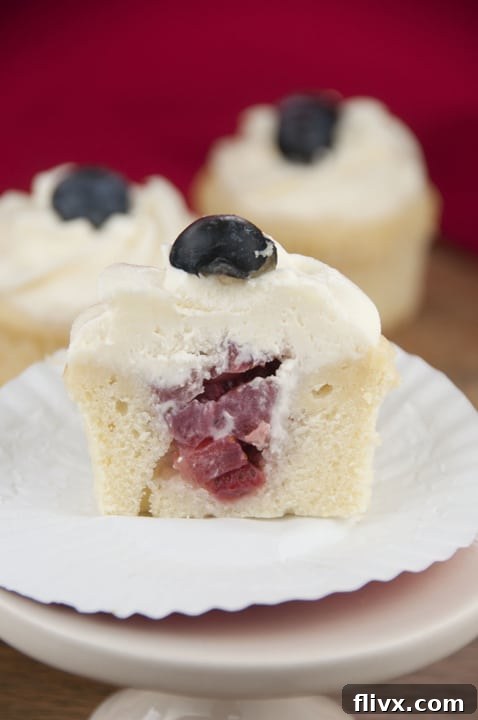 Strawberry filled patriotic cupcakes topped with blueberries and frosting.