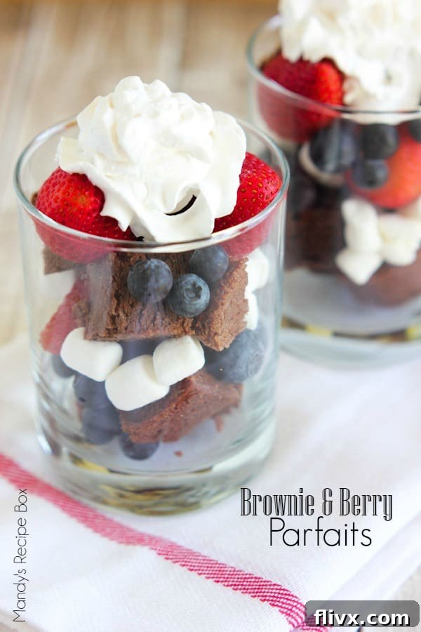 Brownie and berry parfaits layered in a glass with whipped cream.
